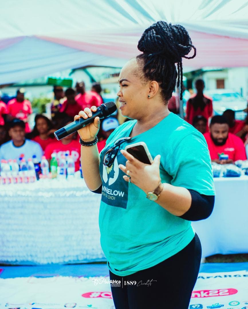 Dr. Didi speaking with a microphone during a breast cancer awareness outreach